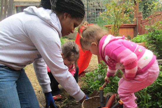 Teacher and children digging in garden.